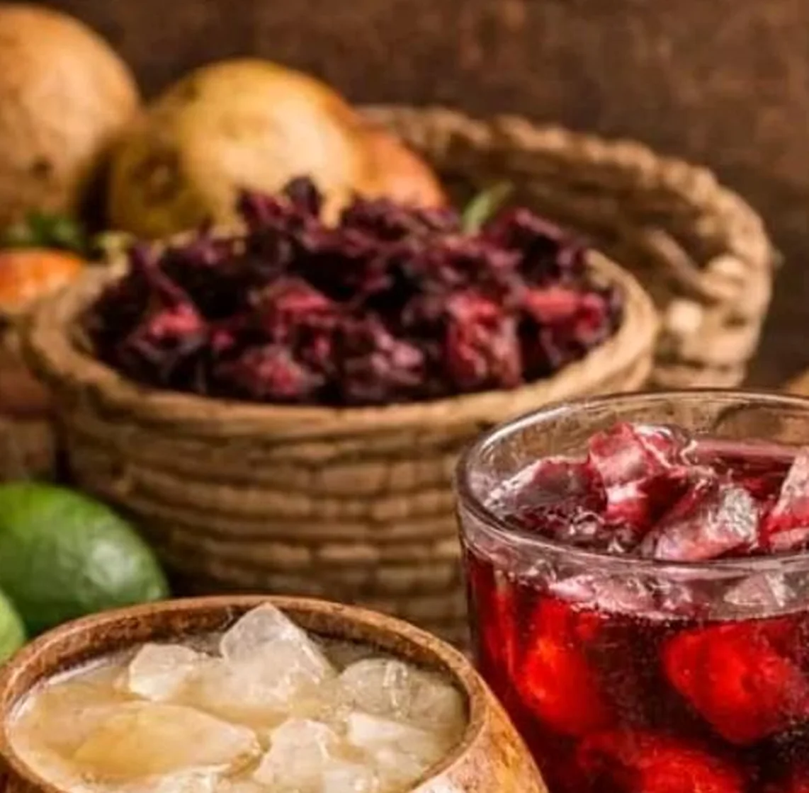 Fleurs d'hibiscus séchées dans un panier tressé, posées près de boissons servies sur glace